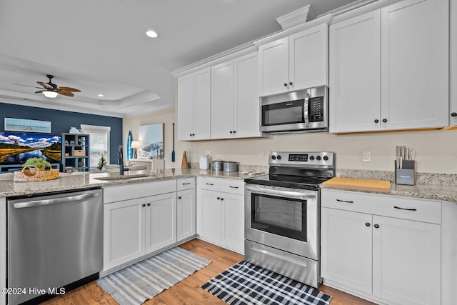 kitchen featuring white cabinetry, ceiling fan, sink, stainless steel appliances, and light hardwood / wood-style flooring