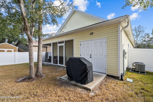 rear view of property featuring a lawn and central air condition unit