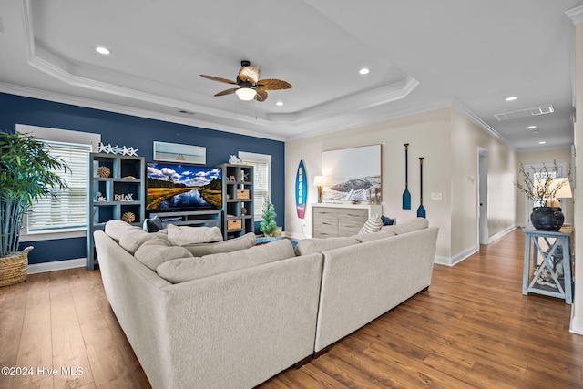 living room featuring wood-type flooring, a tray ceiling, ceiling fan, and crown molding