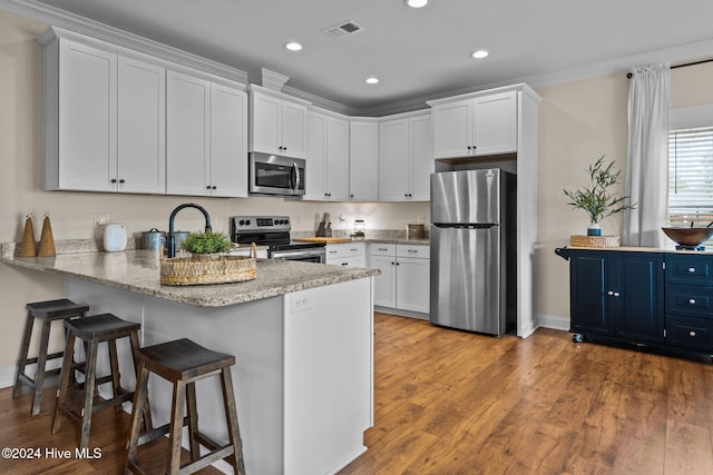 kitchen with white cabinets, sink, light wood-type flooring, kitchen peninsula, and stainless steel appliances