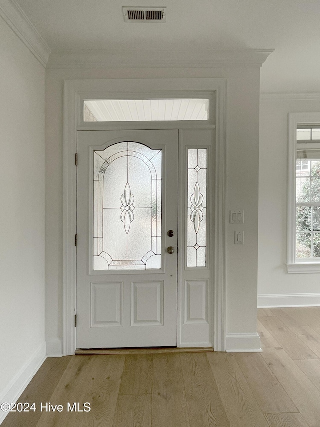 foyer entrance with light hardwood / wood-style flooring and crown molding