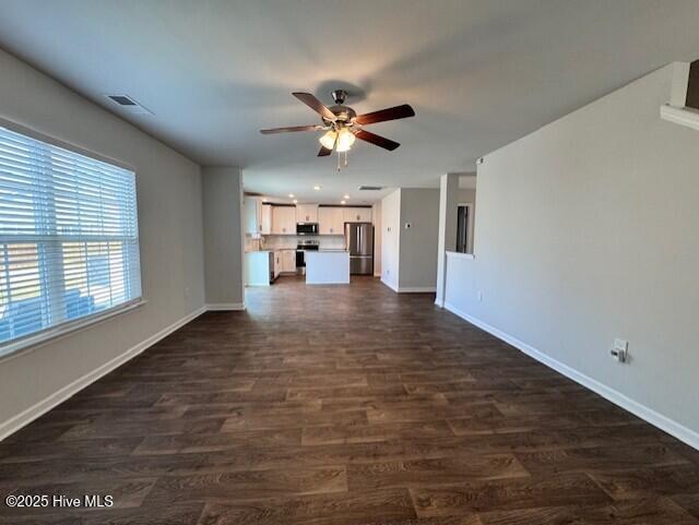 unfurnished living room featuring ceiling fan and dark hardwood / wood-style flooring