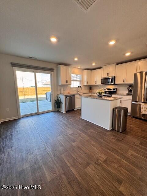 kitchen with a kitchen island, white cabinetry, appliances with stainless steel finishes, and dark hardwood / wood-style flooring