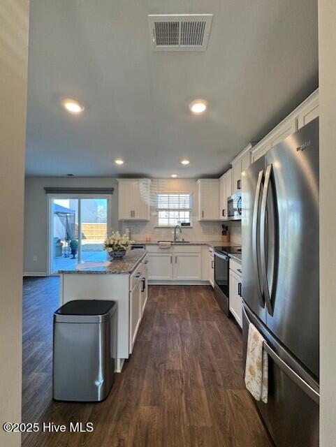 kitchen featuring sink, dark wood-type flooring, appliances with stainless steel finishes, white cabinetry, and light stone countertops