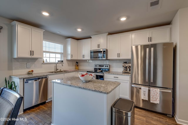 kitchen with a kitchen island, white cabinetry, sink, light stone counters, and stainless steel appliances