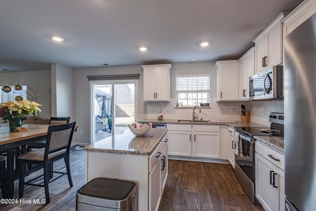 kitchen featuring stainless steel appliances, a kitchen island, sink, and white cabinets