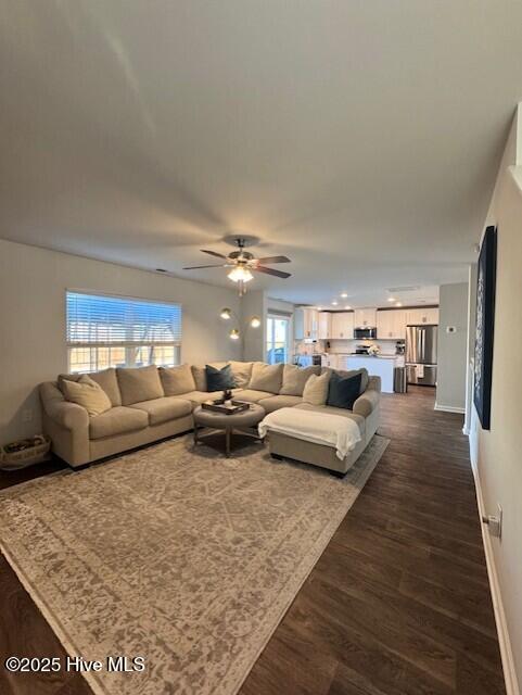 living room featuring dark wood-type flooring and ceiling fan