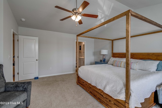 carpeted bedroom featuring ceiling fan, vaulted ceiling, and ensuite bath