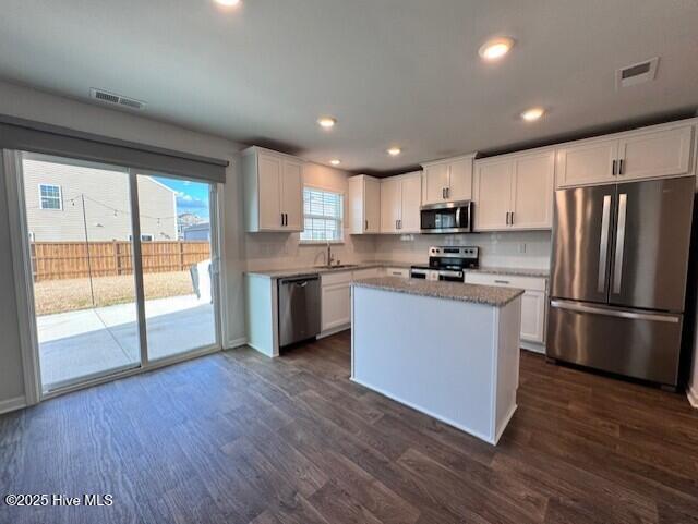 kitchen with sink, a center island, appliances with stainless steel finishes, dark hardwood / wood-style floors, and white cabinets