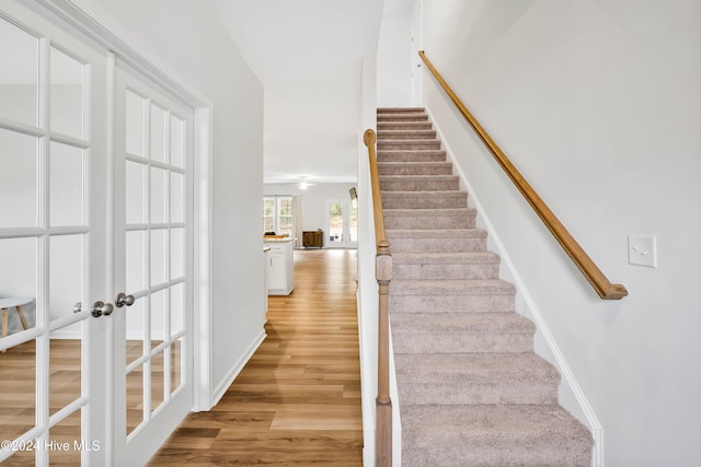 stairway with wood-type flooring and french doors