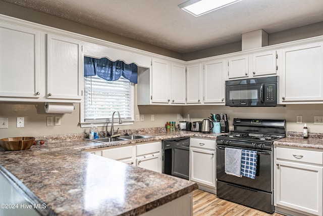 kitchen featuring white cabinetry, sink, black appliances, and light hardwood / wood-style floors