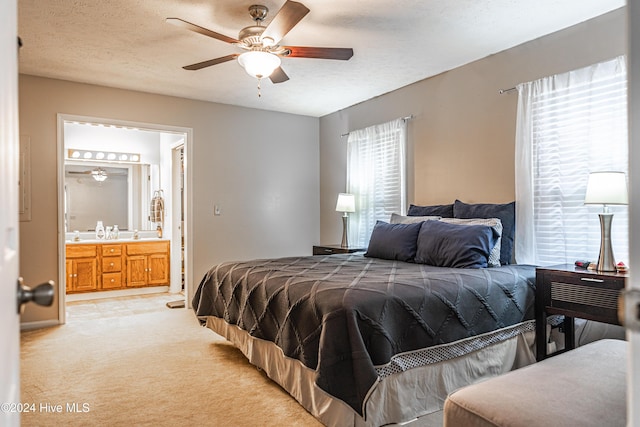 carpeted bedroom with multiple windows, ensuite bathroom, ceiling fan, and a textured ceiling