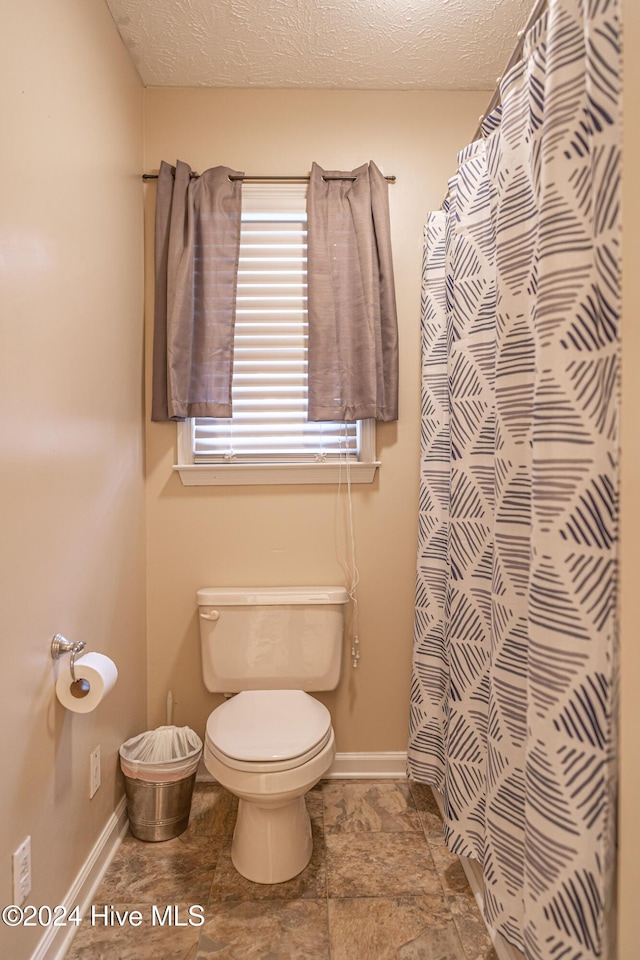 bathroom with a shower with shower curtain, a textured ceiling, and toilet