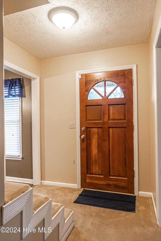 entryway with a textured ceiling and light carpet