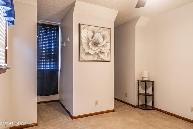 hall with light carpet and a textured ceiling