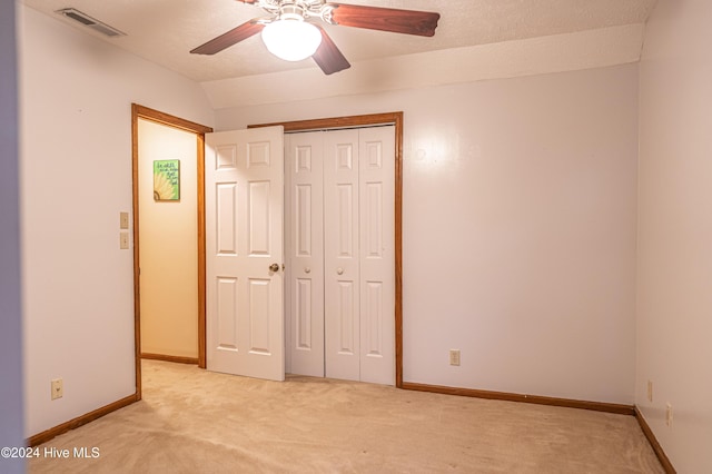 unfurnished bedroom featuring a textured ceiling, light colored carpet, ceiling fan, a closet, and lofted ceiling