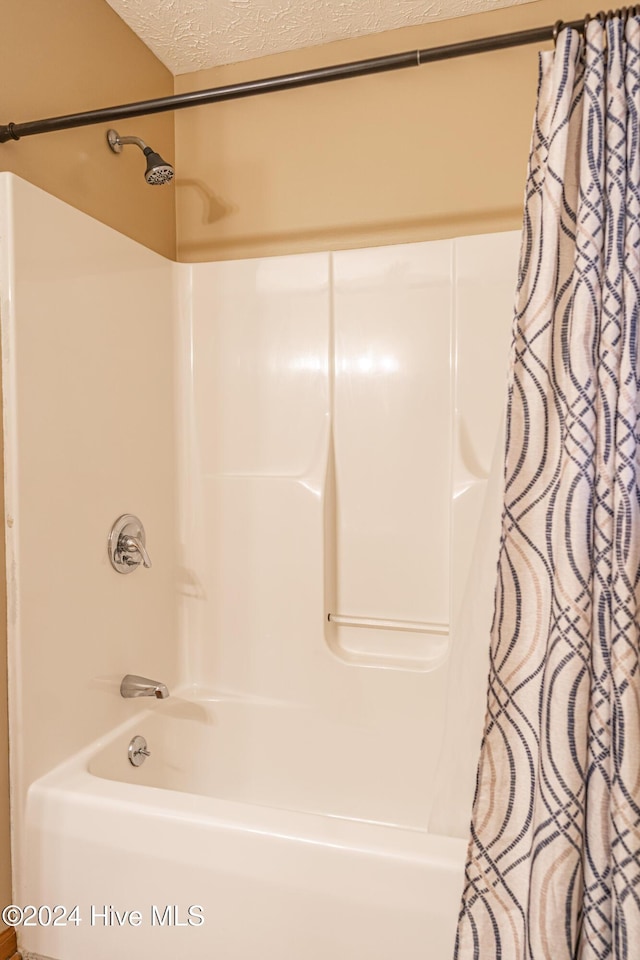 bathroom with shower / bath combo with shower curtain and a textured ceiling