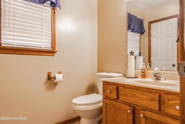 bathroom featuring a textured ceiling, vanity, and toilet