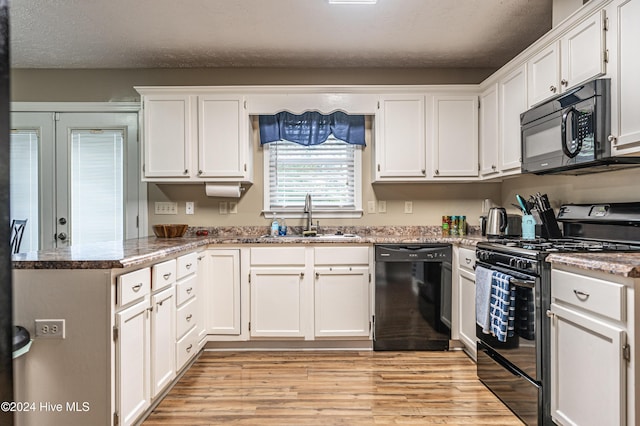 kitchen with black appliances, sink, light hardwood / wood-style flooring, stone countertops, and white cabinetry