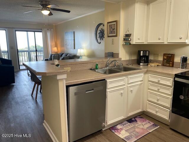 kitchen featuring open floor plan, a peninsula, stainless steel appliances, light countertops, and a sink