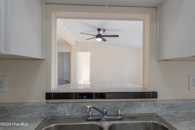 kitchen with ceiling fan, white cabinetry, lofted ceiling, and sink