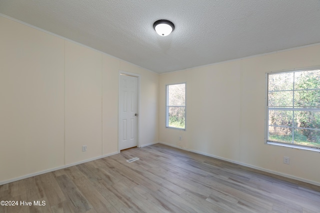 spare room with plenty of natural light, a textured ceiling, and light hardwood / wood-style flooring