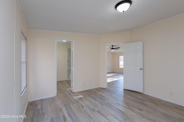 empty room with ceiling fan, light hardwood / wood-style floors, crown molding, and a textured ceiling