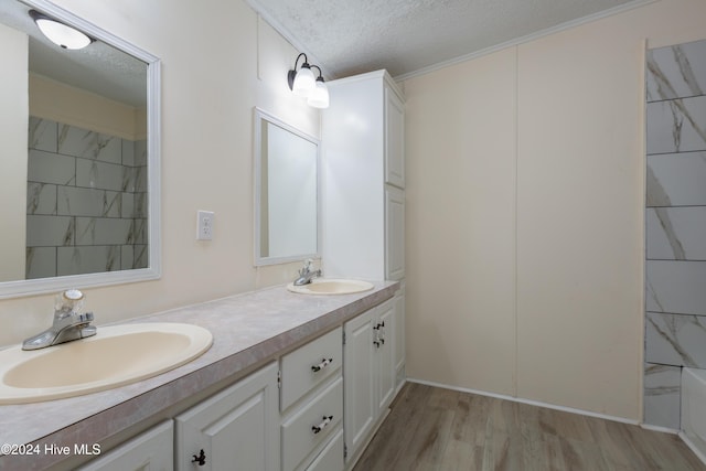 bathroom featuring hardwood / wood-style floors, vanity, crown molding, and a textured ceiling