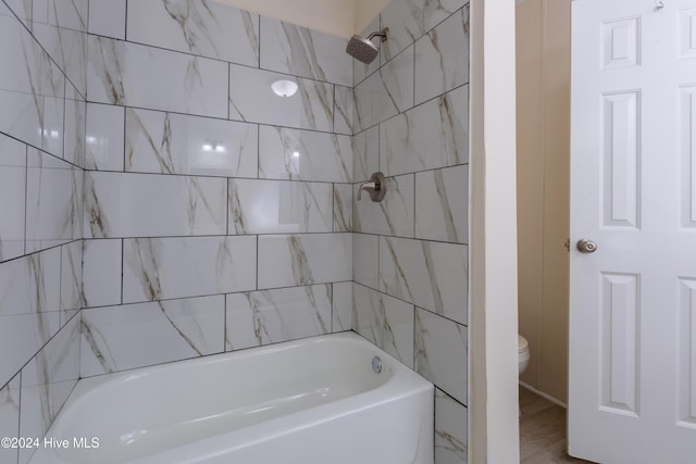 bathroom with tiled shower / bath combo and toilet