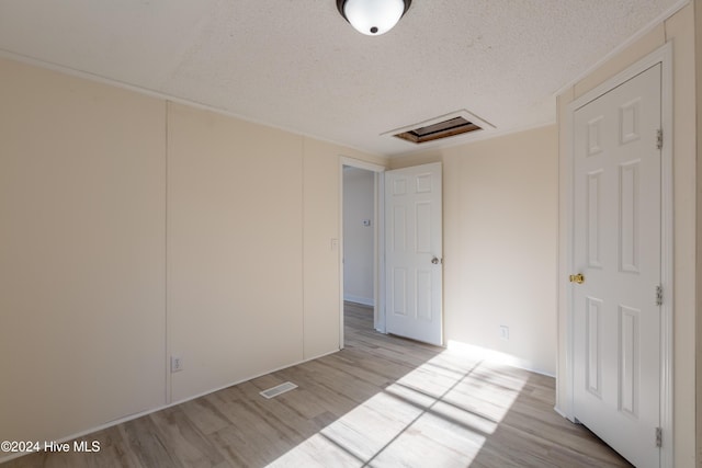 spare room featuring light wood-type flooring and a textured ceiling