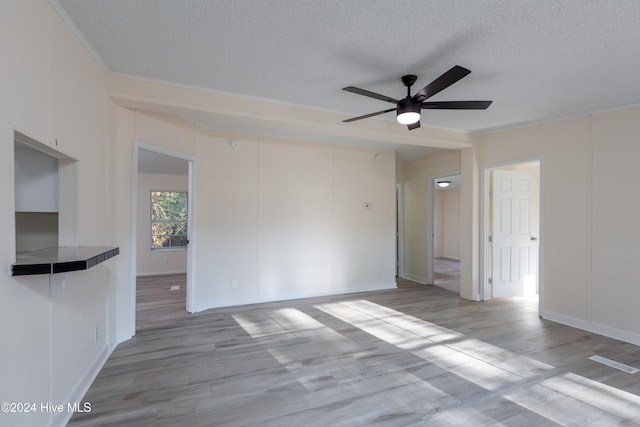 unfurnished room featuring a textured ceiling, light hardwood / wood-style floors, and ceiling fan