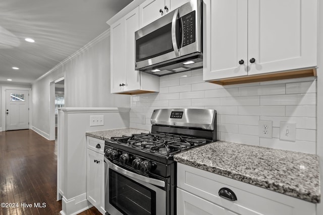 kitchen with light stone countertops, dark hardwood / wood-style flooring, ornamental molding, stainless steel appliances, and white cabinets