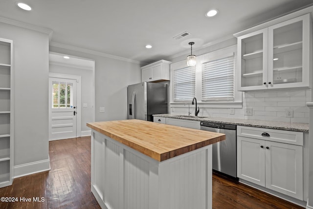 kitchen with appliances with stainless steel finishes, sink, white cabinets, a center island, and butcher block countertops