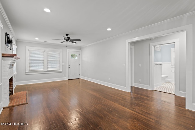 unfurnished living room featuring a brick fireplace, ceiling fan, dark wood-type flooring, and crown molding