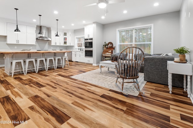 living room featuring sink, light hardwood / wood-style flooring, and ceiling fan