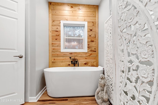 bathroom with wood-type flooring, a tub, and wood walls