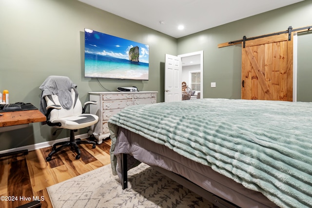 bedroom featuring wood-type flooring and a barn door