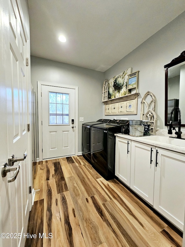 washroom featuring cabinets, washer and clothes dryer, sink, and light wood-type flooring