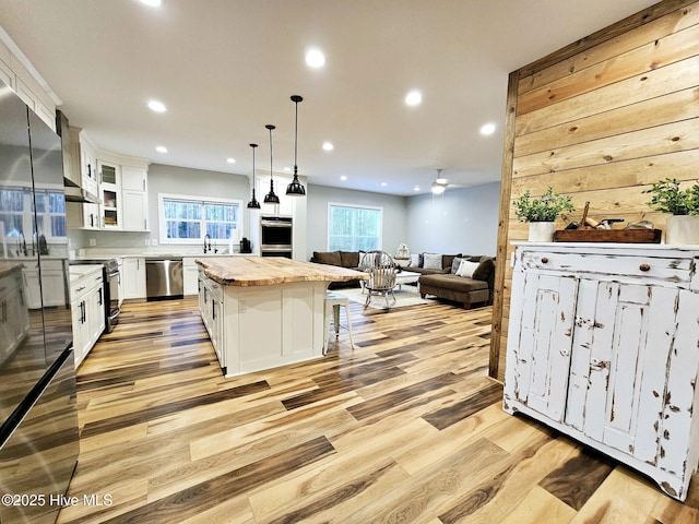 kitchen featuring a breakfast bar, decorative light fixtures, a center island, stainless steel appliances, and white cabinets