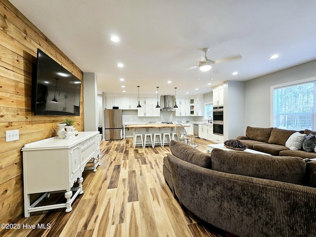 living room with ceiling fan, sink, and light wood-type flooring