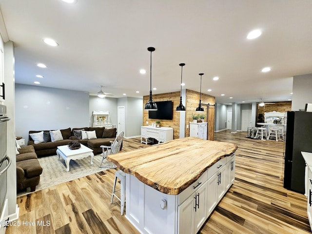 kitchen with white cabinetry, a kitchen bar, a kitchen island, and light hardwood / wood-style flooring