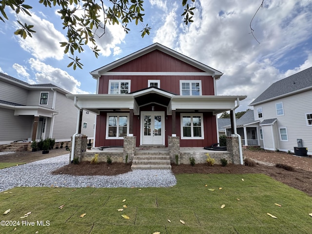 view of front of property featuring cooling unit, a front lawn, and covered porch