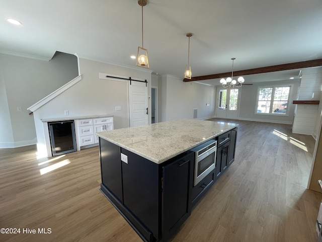 kitchen featuring beverage cooler, a barn door, a center island, light hardwood / wood-style floors, and white cabinetry