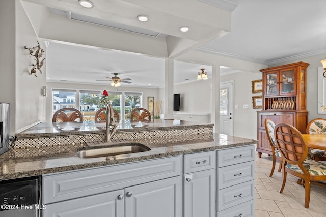 kitchen featuring decorative backsplash, ceiling fan, sink, black dishwasher, and white cabinetry