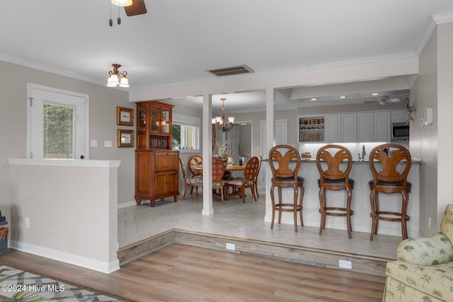 dining space featuring ceiling fan with notable chandelier, light hardwood / wood-style flooring, and ornamental molding