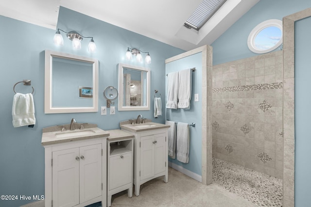 bathroom featuring lofted ceiling with skylight, tile patterned flooring, vanity, and tiled shower