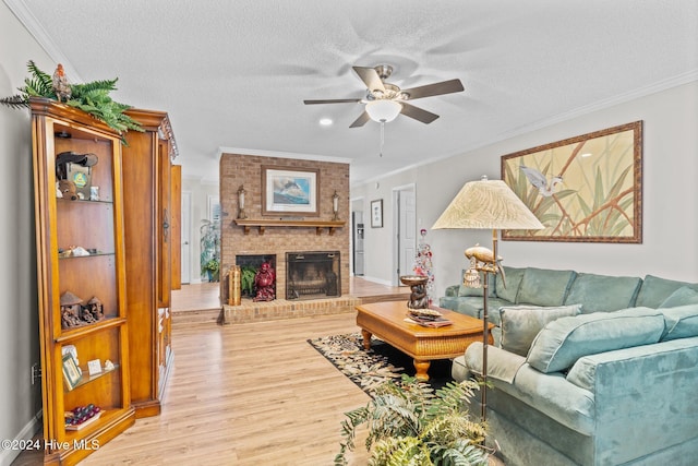 living room featuring a fireplace, a textured ceiling, light wood-type flooring, and crown molding