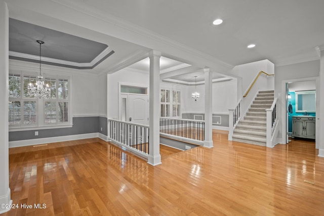 interior space with hardwood / wood-style floors, decorative columns, an inviting chandelier, and ornamental molding