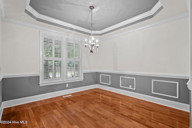 empty room featuring hardwood / wood-style floors, a raised ceiling, and crown molding