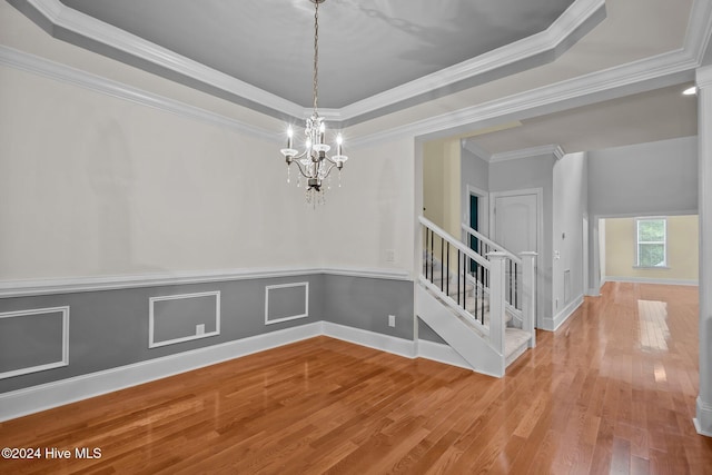 unfurnished room with a chandelier, crown molding, a tray ceiling, and wood-type flooring